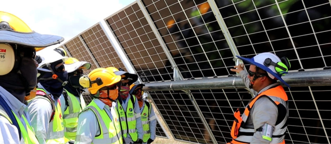Trabajadores con cascos de seguridad reciben capacitación en instalación de paneles solares en parque Guayepo III, Atlántico
