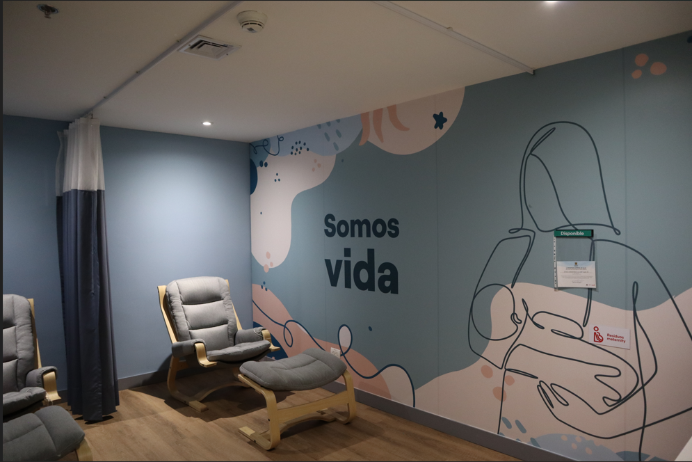 Sala de lactancia de Enel con sillas reclinables, cortinas de privacidad y mural Somos vida.