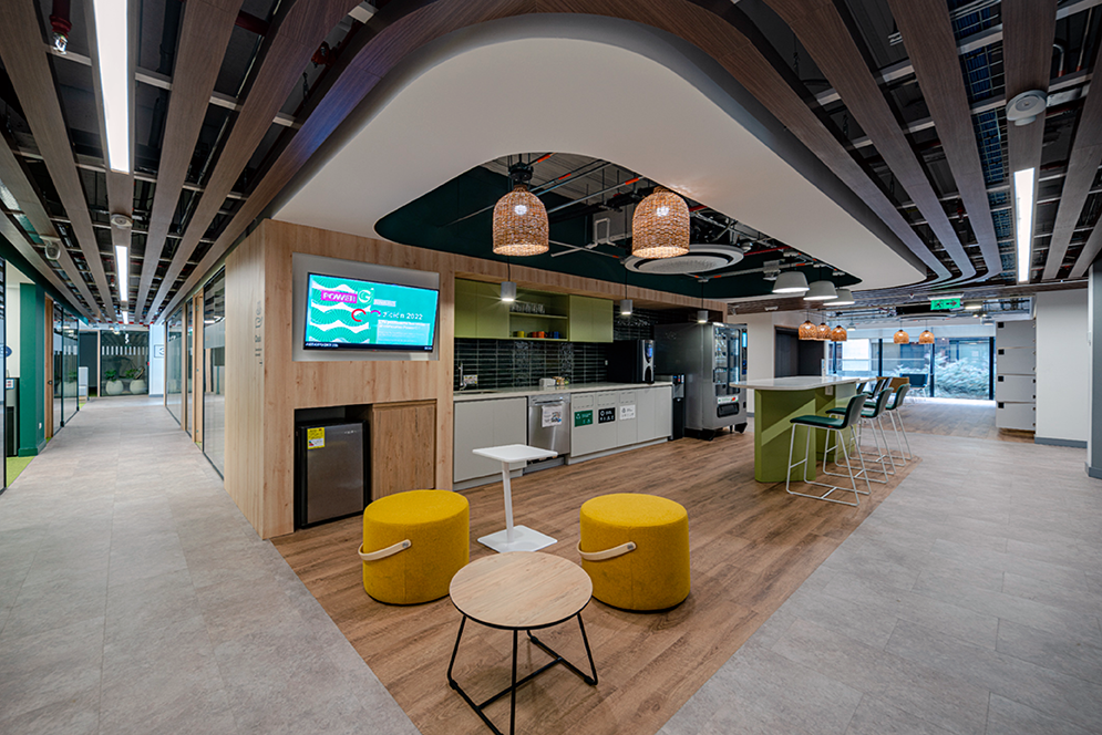 Zona colaborativa de las oficinas de Enel con mesas, cafetería y espacios abiertos de descanso.