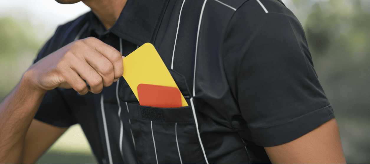 Árbitro sostiene tarjetas amarilla y roja como referencia a hábitos de ahorro y seguridad eléctrica en casa.