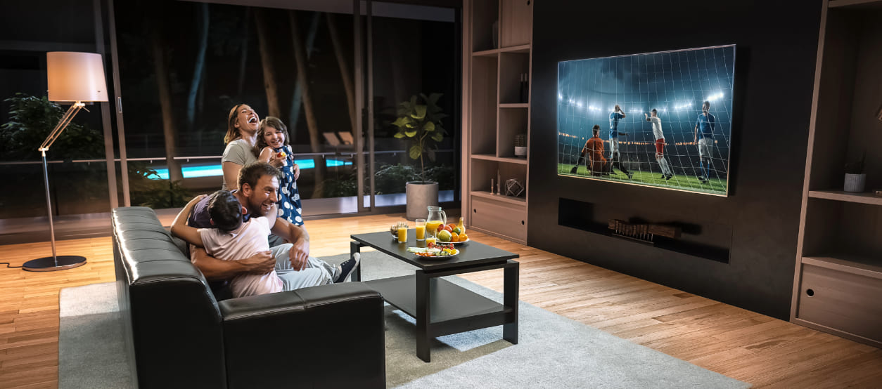 Familia ve un partido de fútbol en casa con el televisor encendido durante el Mundial.