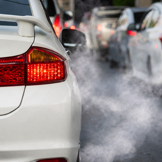 Automóviles emitiendo partículas contaminantes al aire debido al uso de combustibles fósiles.