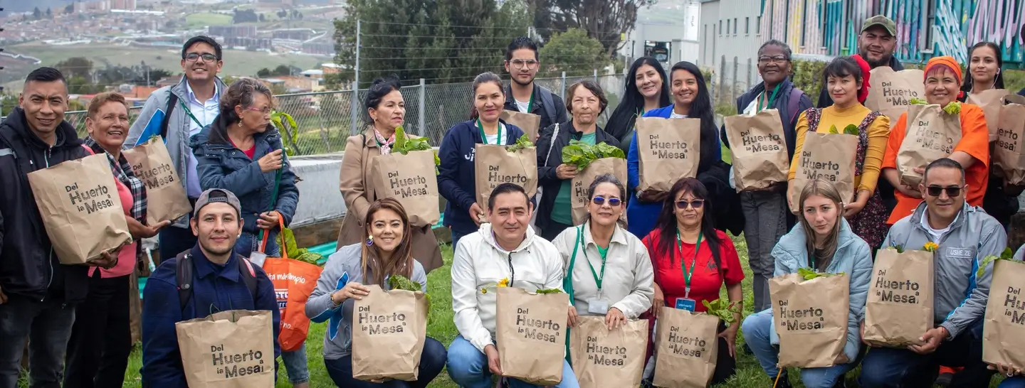 Personas de la comunidad recibiendo las verduras cosechadas en el huerto de la electroterminal de Usme.