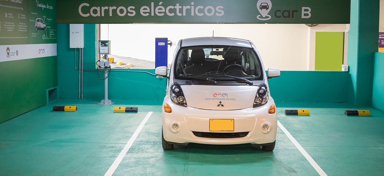 Vehículo eléctrico estacionado en punto de recarga Enel Colombia con señalización de carros eléctricos