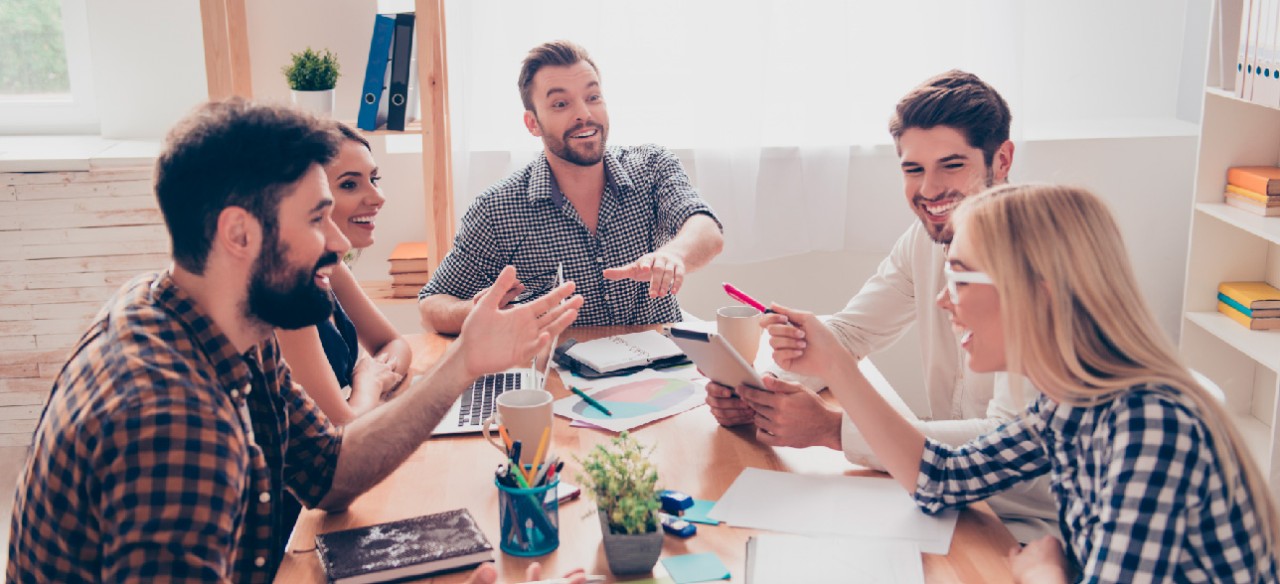 EquiEquipo de jóvenes emprendedores reunidos en mesa de trabajo compartiendo ideaspo de trabajo