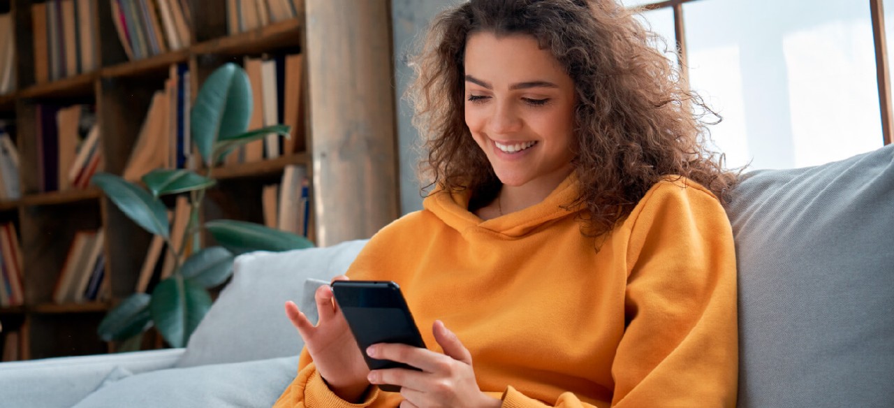 Mujer usando la App Enel Clientes Colombia en su celular para consultar su factura de energía desde casa
