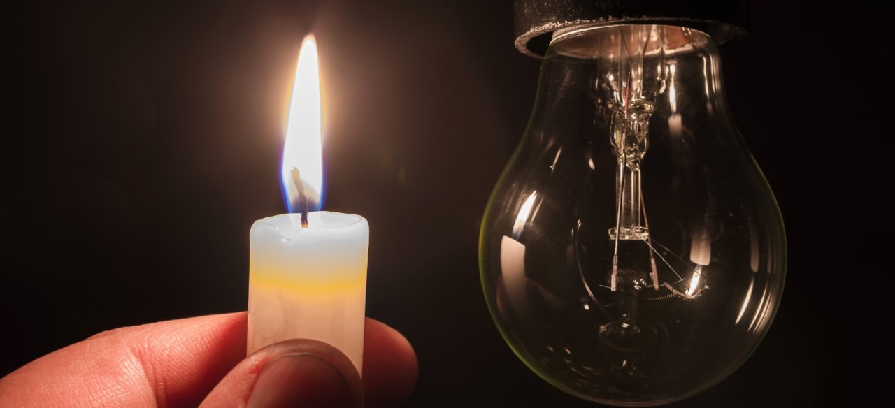 Vela encendida cerca de un bombillo apagado por una falla eléctrica en casa