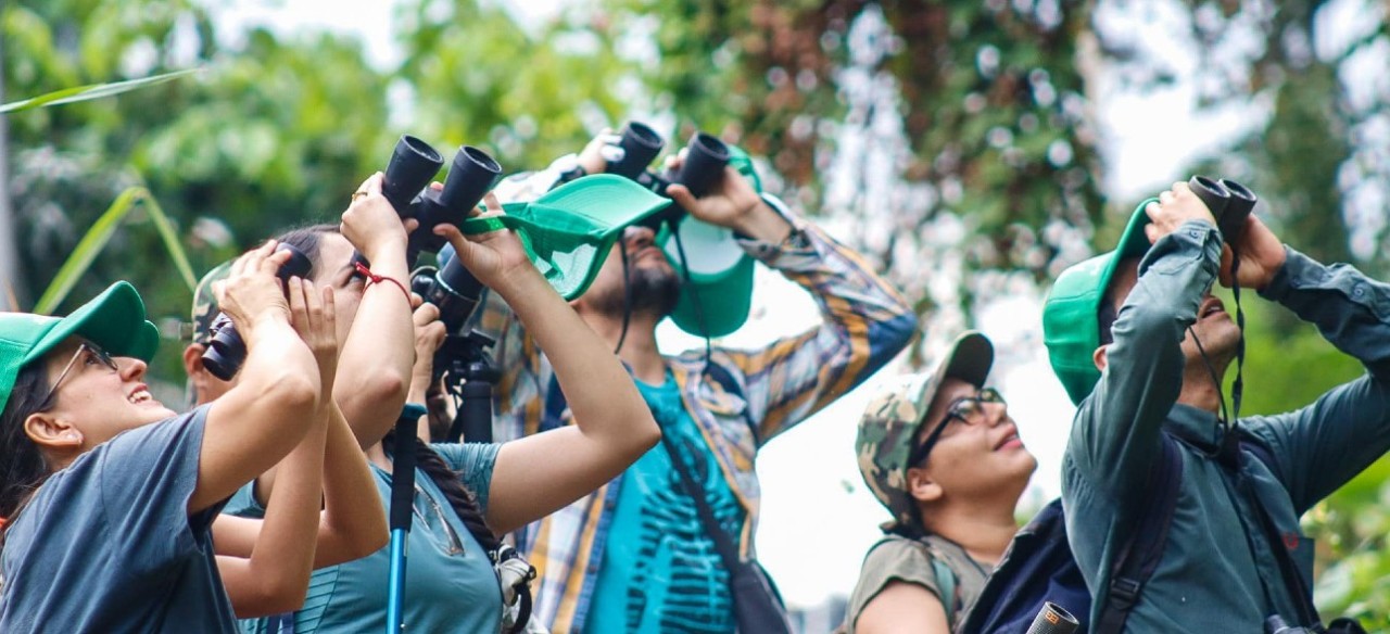 Jóvenes observando aves con binoculares durante el Global Big Day en una central de Enel Colombia
