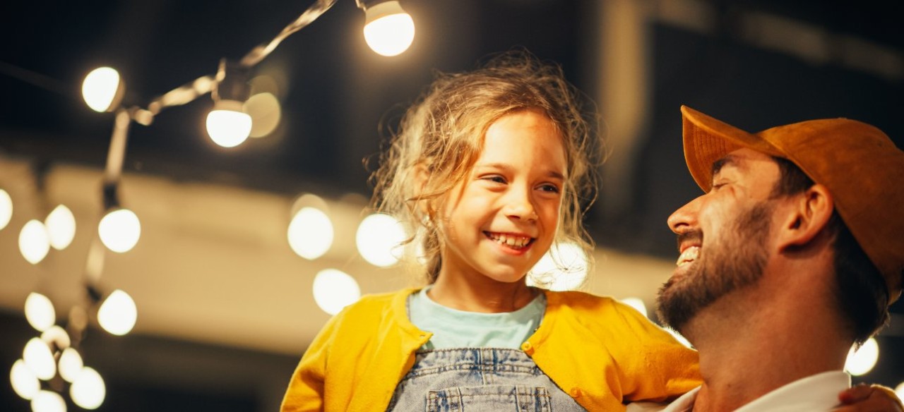Padre e hija sonriendo bajo las luces encendidas con la energía de Enel Colombia.