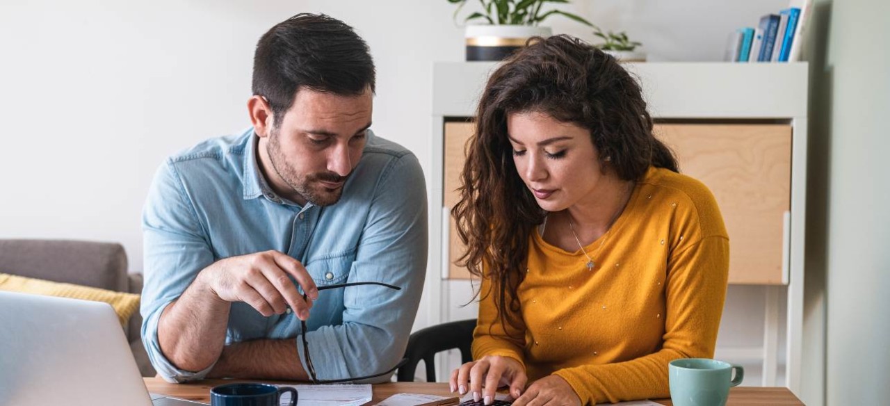 Pareja calculando sus gastos y deudas para realizar un acuerdo de pago de su factura de energía y ponerse al día.