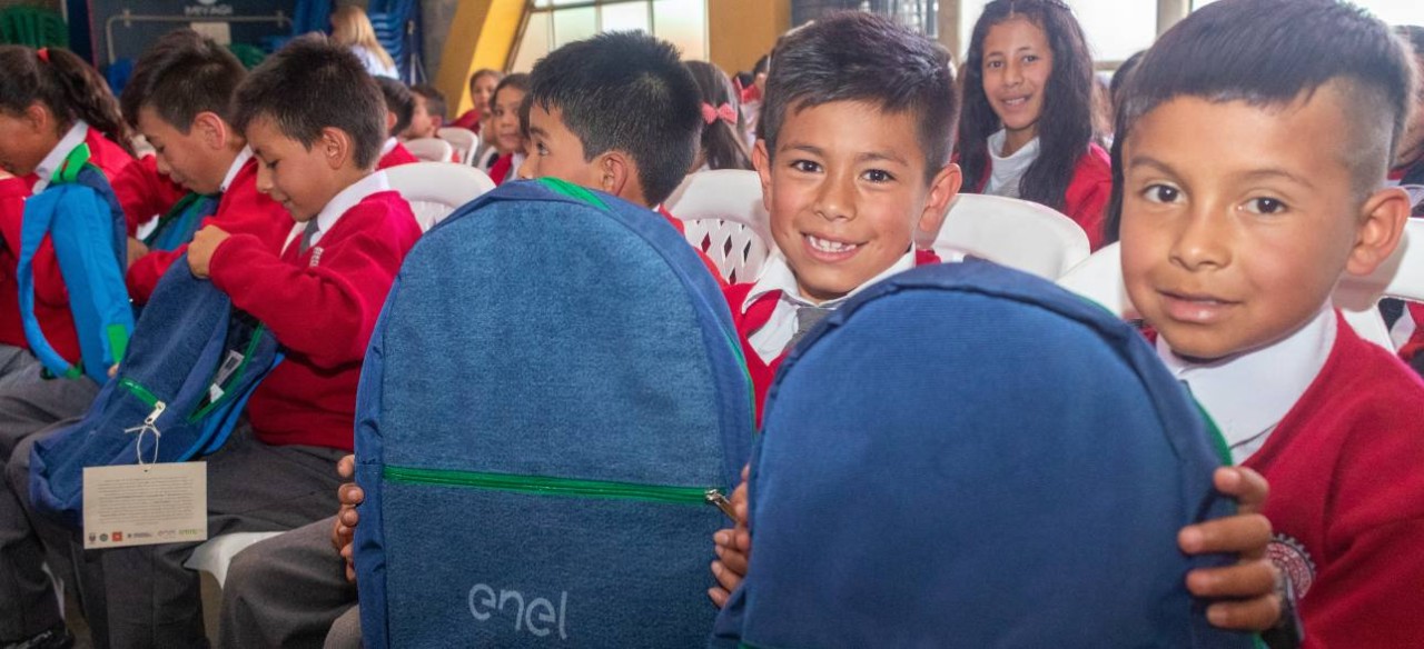 Niños sonriendo con la maleta del kit escolar de ‘Tejiendo sueños con energía’, una iniciativa de Enel Colombia.