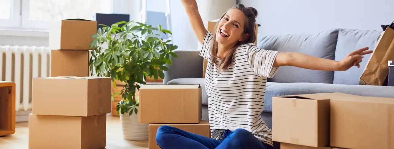 Una mujer feliz desempacando sus pertenencias después de independizarse.