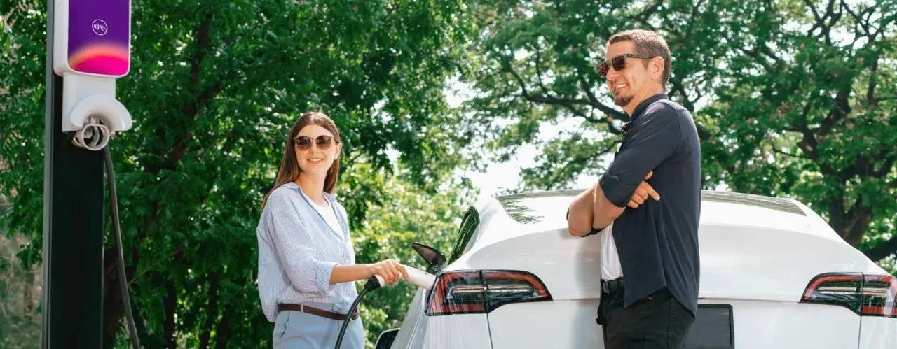 Dos personas cargando su vehículo eléctrico 