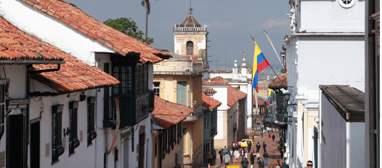 Fotografía de calle con banderas de Colombia izadas en las fachadas
