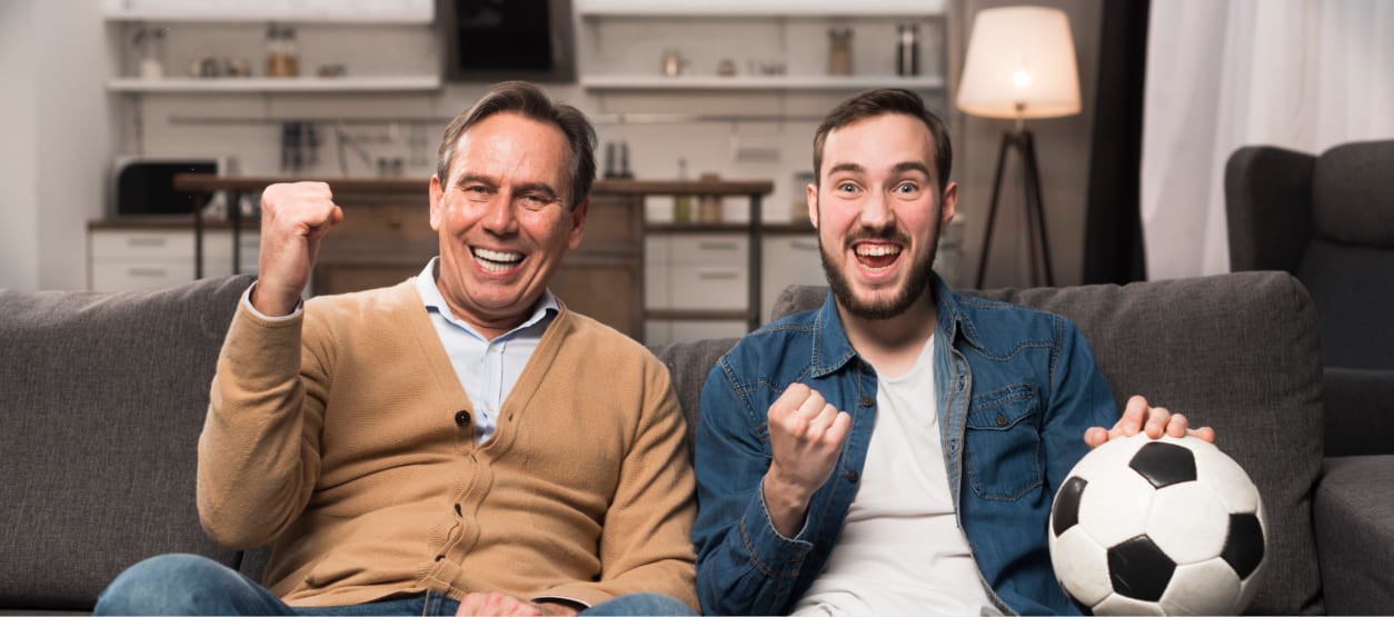 Padre e hijo celebran un partido de fútbol en casa mientras disfrutan el Mundial en familia.