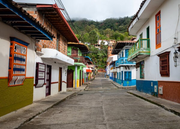 Calle de un pueblo colombiano con casas coloridas y montañas al fondo, representando una zona rural