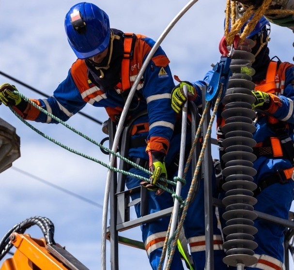 Técnico de Enel Colombia con arnés de seguridad realizando mantenimiento en poste de red eléctrica
