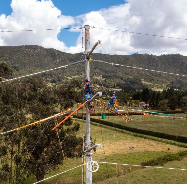 Técnico de Enel Colombia con arnés de seguridad realizando mantenimiento en poste de red eléctrica