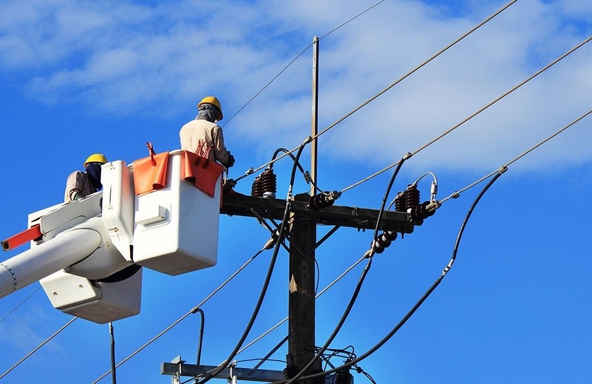 Técnico de Enel Colombia con arnés de seguridad realizando mantenimiento en poste de red eléctrica