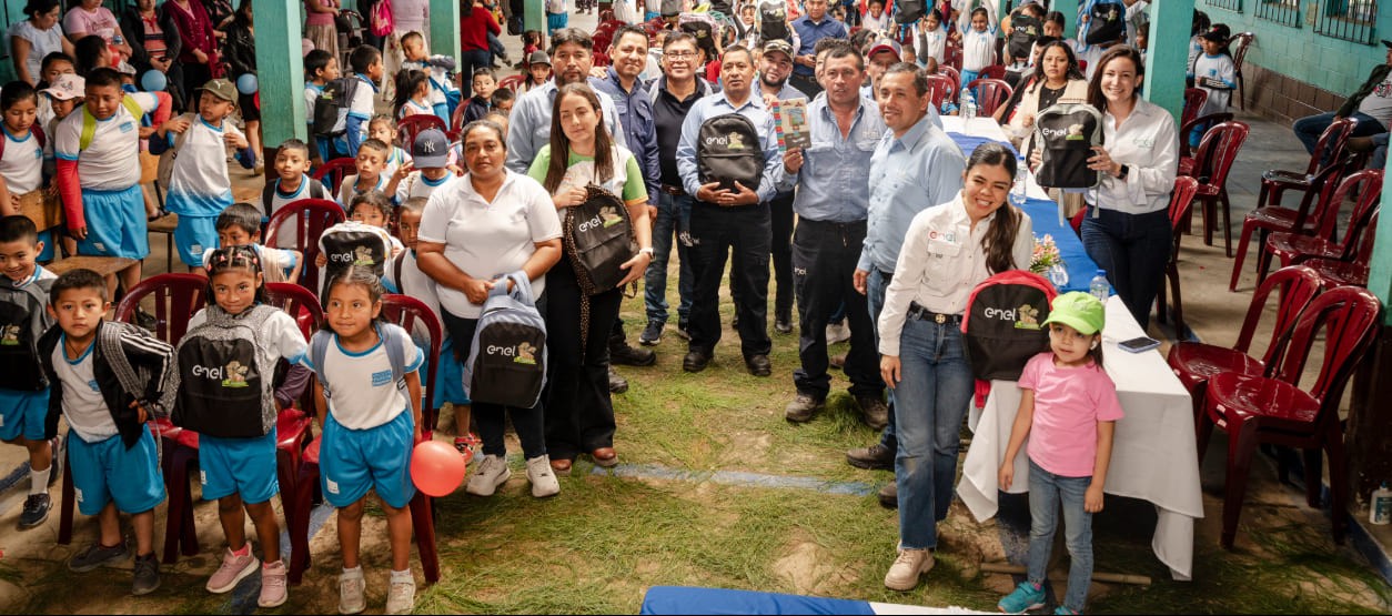 Niños y representantes de Enel Guatemala en entrega de mochilas escolares del programa Tejiendo Sueños con Energía, Baja Verapaz
