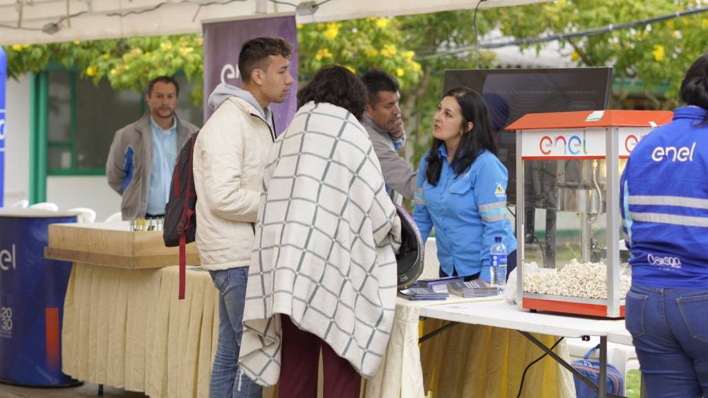 Asistentes de la comunidad conversan con colaboradores de Enel en el stand de la feria comunitaria