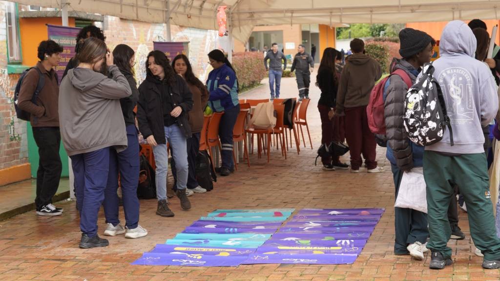 Jóvenes recorren un juego de piso didáctico durante la feria de las comunidades cuidadoras